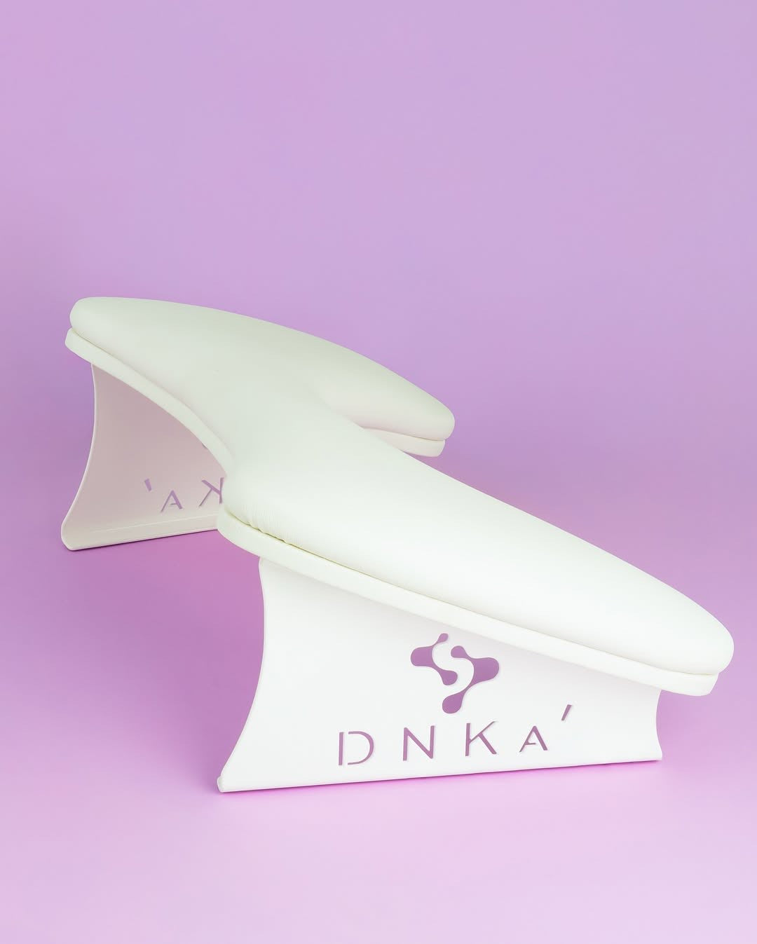 White ergonomic wrist rest on a light purple background. Armrest in white