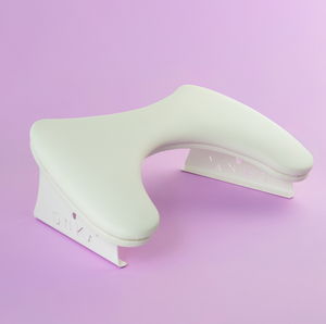 White ergonomic wrist rest on a light purple background. Armrest in white