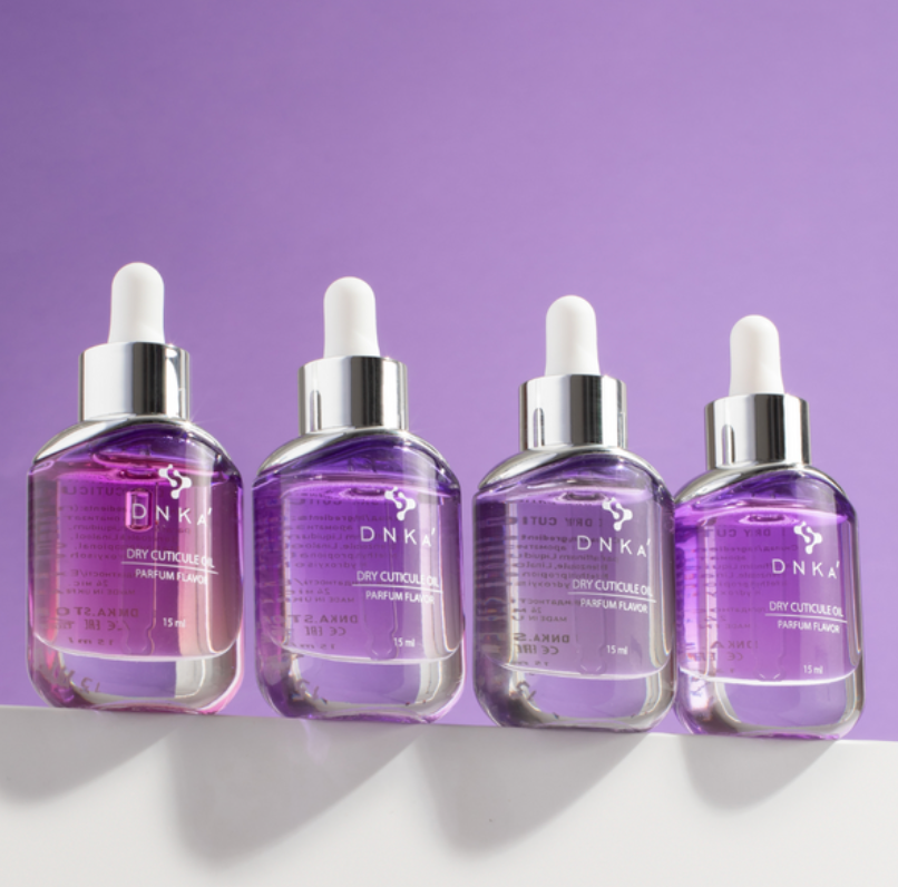 Four DNKA perfume flacons on a white surface with a purple background