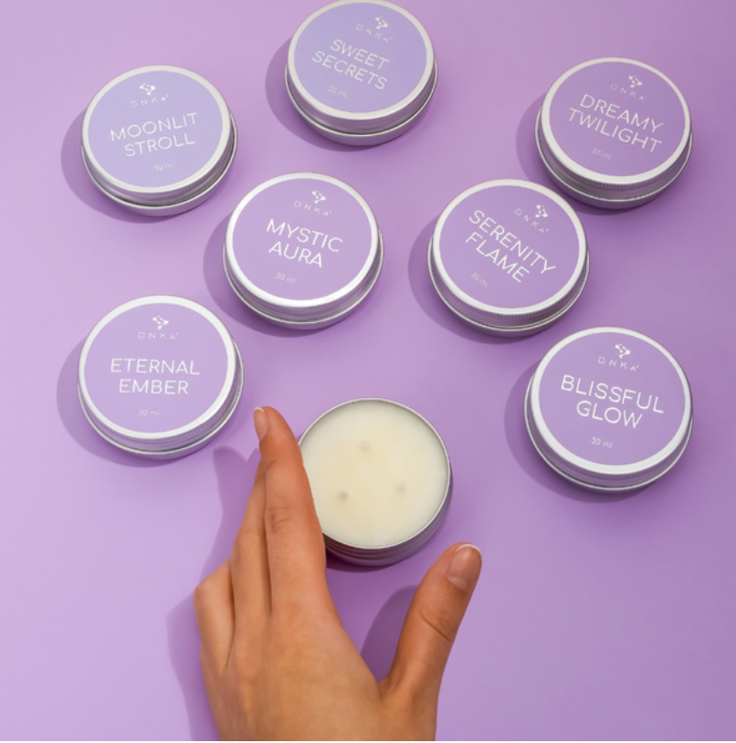 Collection of small containers with lids on a purple background, one being held by a hand.