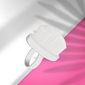 White facial cleansing brush on a pink and gray gradient background