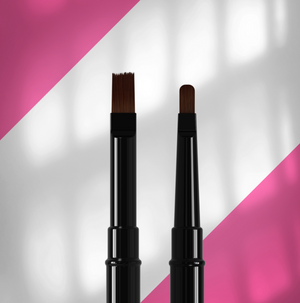 Two makeup brushes with black handles on a pink and white background