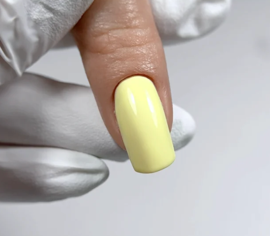 Close-up of a hand with a yellow nail tip, wearing a white glove on a light gray background