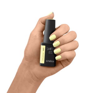 Hand holding a black nail polish bottle with 'kinetics' branding on a white background