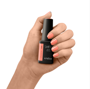Hand holding a bottle of Kinetics Shield Gel Polish with matching nail color on a white background