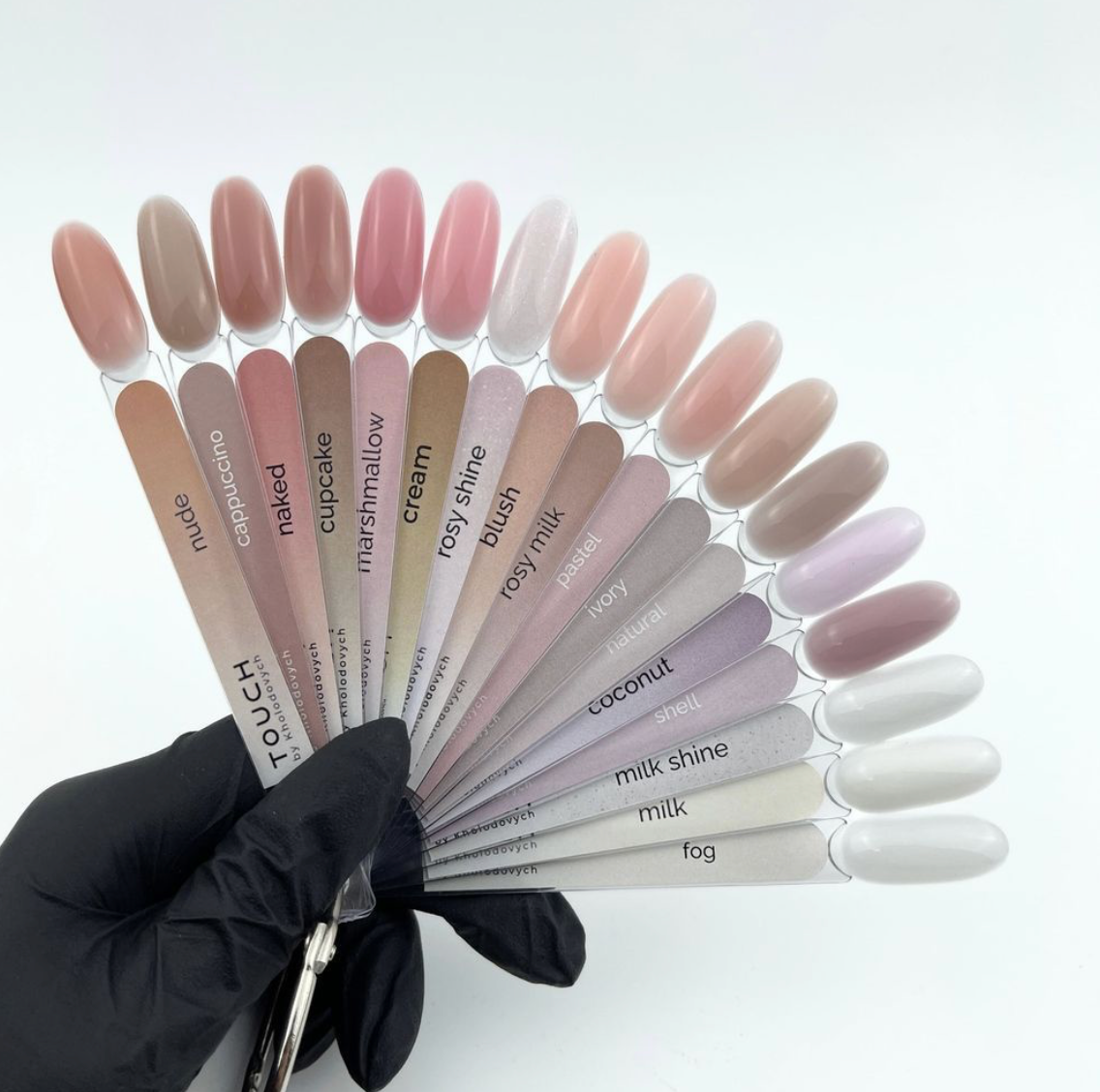 Nail color swatches held by a gloved hand on a white background