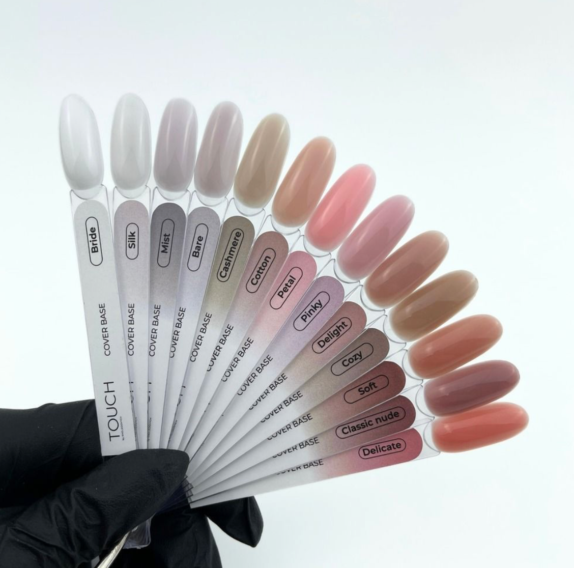 Nail color swatches held by a gloved hand on a white background