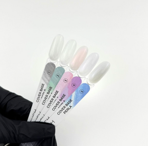 Set of nail polish bottles with gradient colors held by a gloved hand on a white background