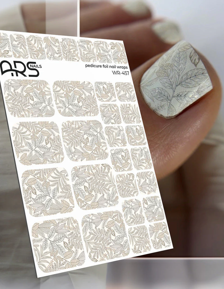 Nail art foil sheet with floral design held by a hand with a manicured nail.