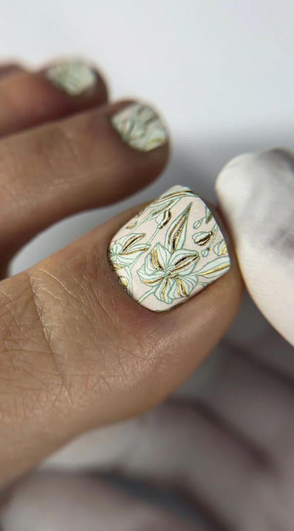 Close-up of a hand with a decorative nail design on a white background