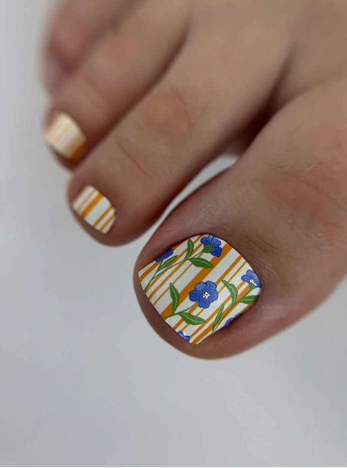 Nail with floral and striped design on a neutral background