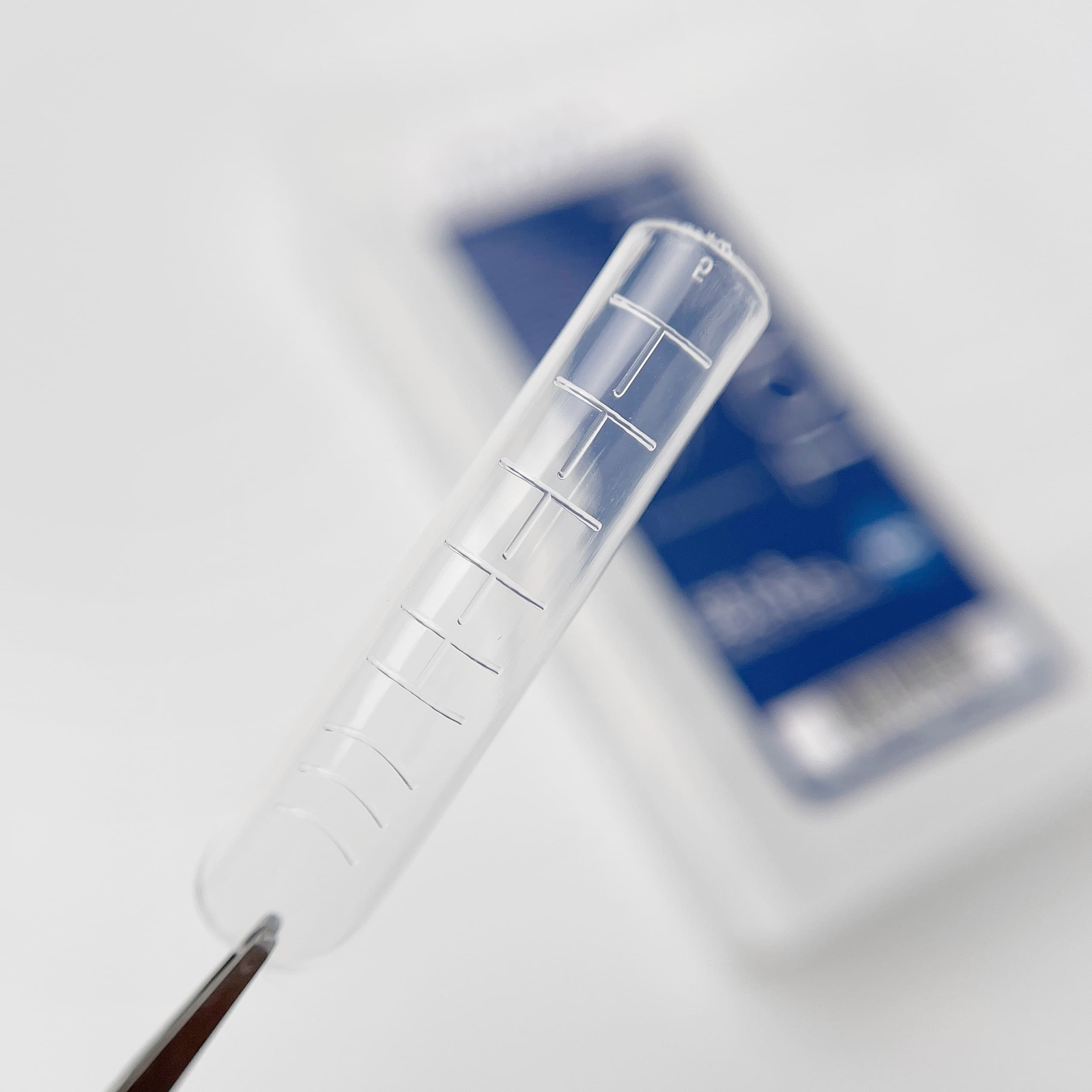 Close-up of a clear plastic ruler on a white surface with a blurred smartphone in the background.