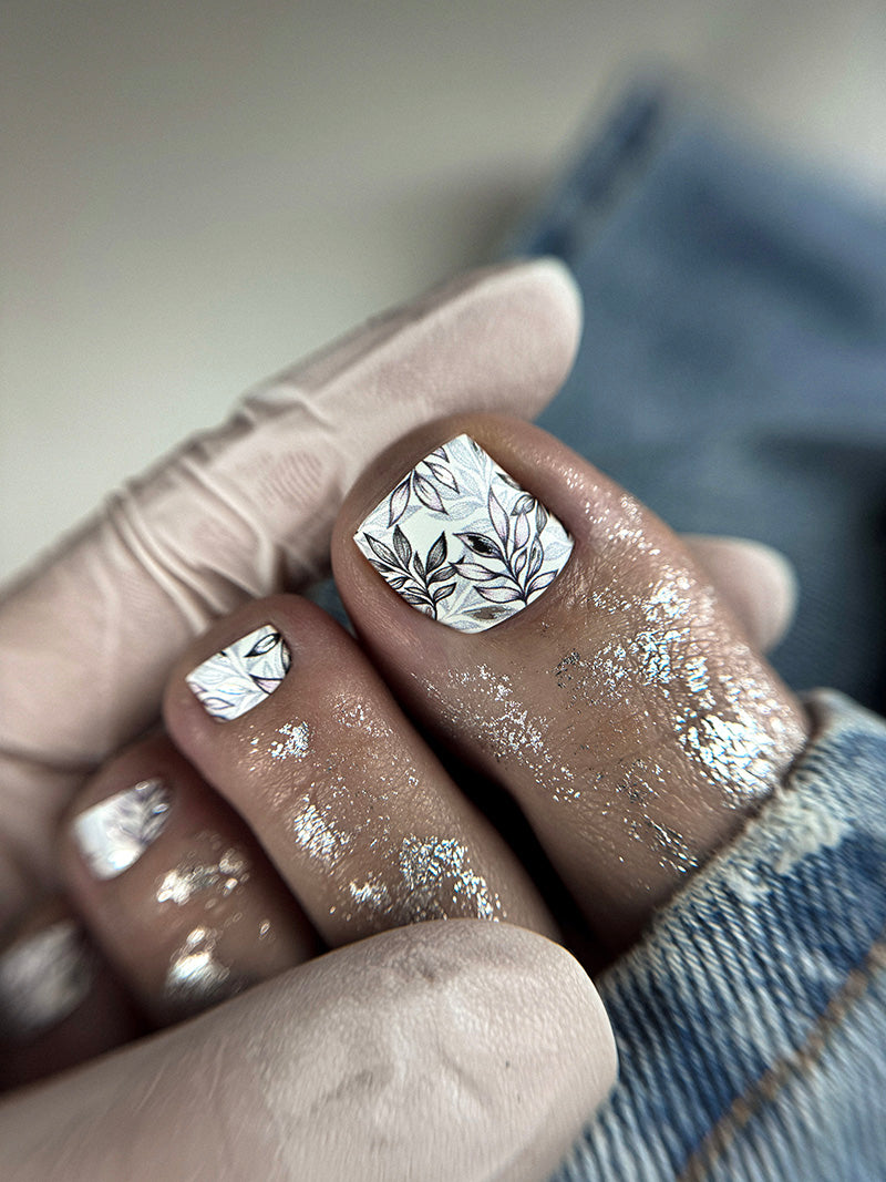 Close-up of a hand with silver nail art and a textured surface background