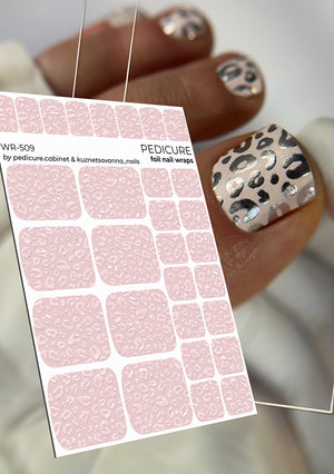 Sheet of pink nail wraps with leopard print design held by a hand with silver nail polish.