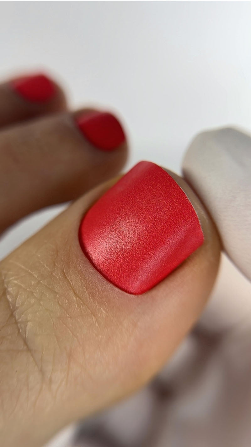 Close-up of a hand with red nail polish on a white background