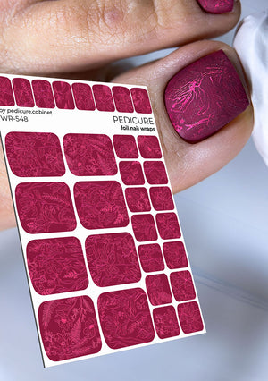 Sheet of pink nail wraps held by a hand with pink nail polish on a light gray background