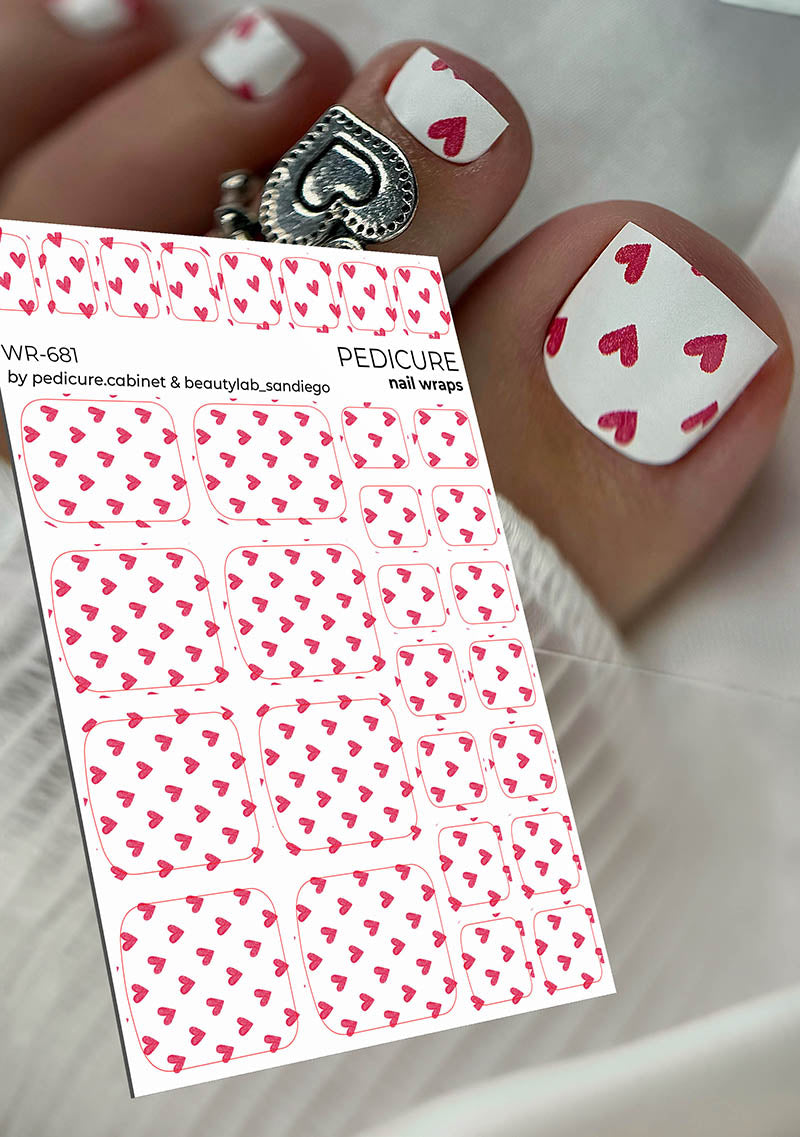 Sheet of heart-patterned nail wraps with a hand displaying decorated nails.