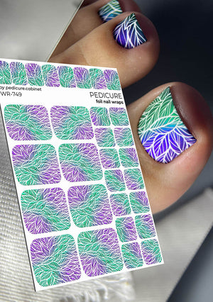 Foil nail wraps with purple and green leaf pattern on a pedicure cabinet, with a hand showing nails with similar design.