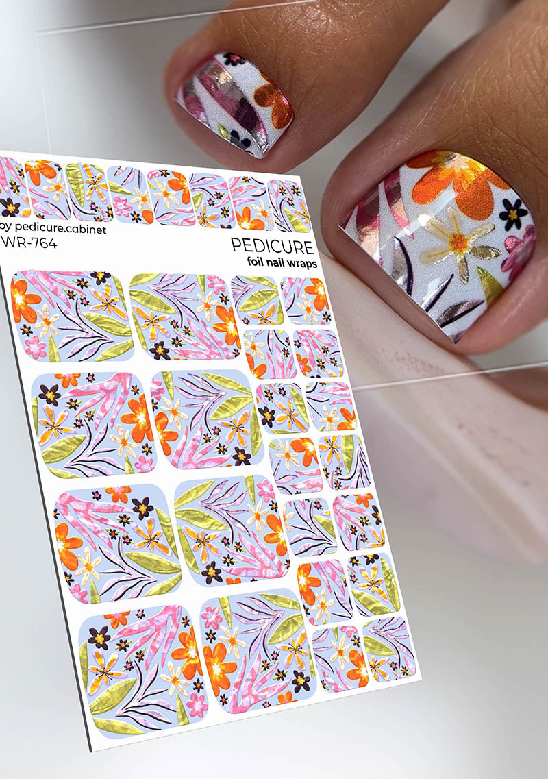 Foil nail wraps with floral designs next to a hand with decorated nails.