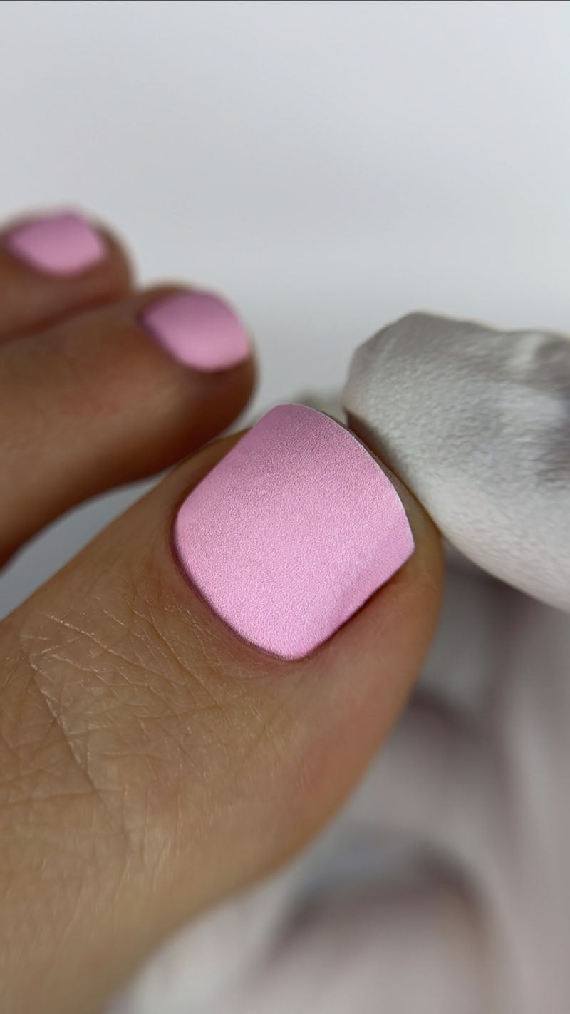 Close-up of a foot with pink nail polish on a white background