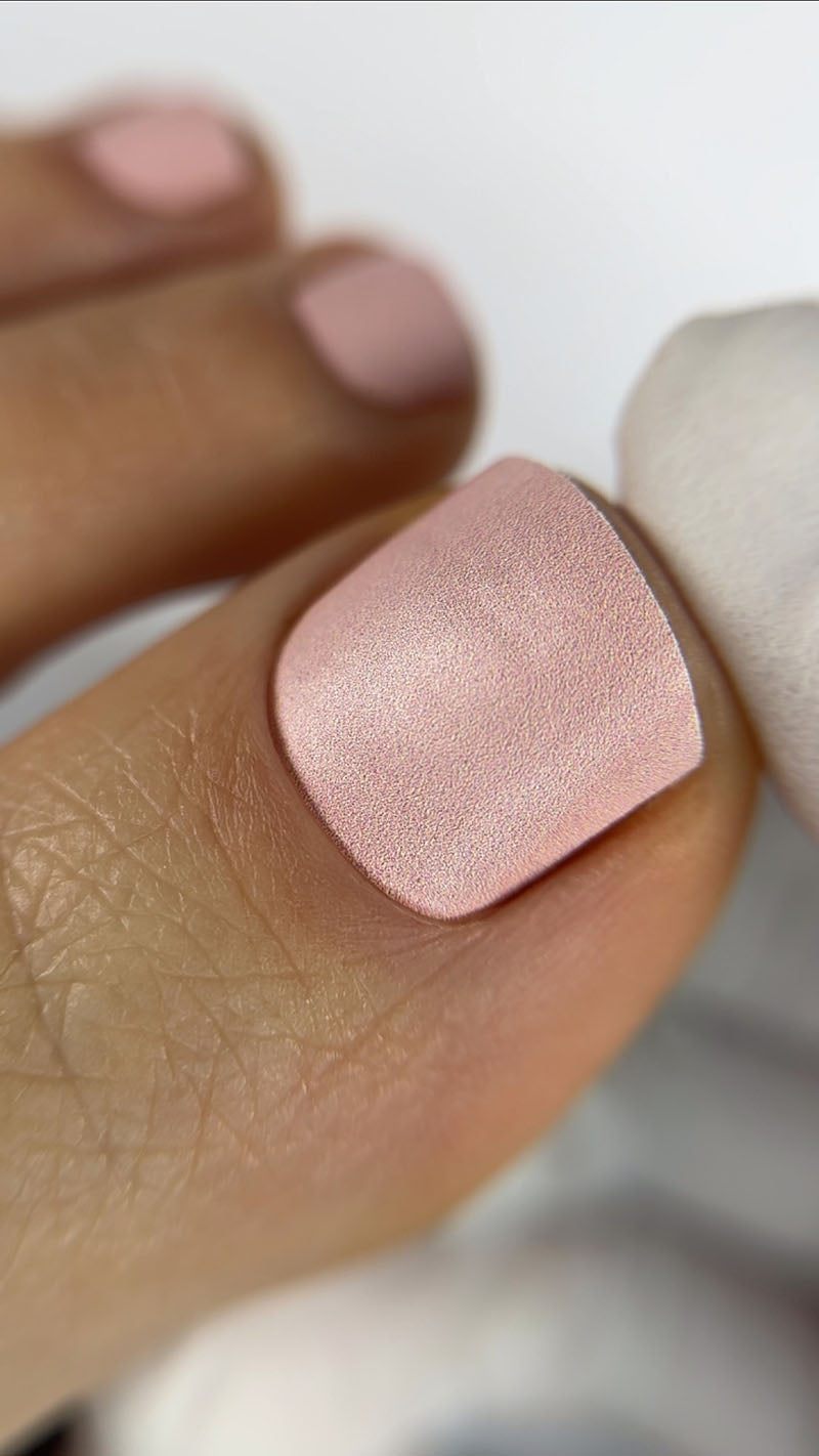 Close-up of a hand with a pink nail polish on a blurred background