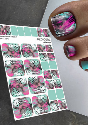 Nail wrap sheet with pink and green design held by a hand with matching nail art.
