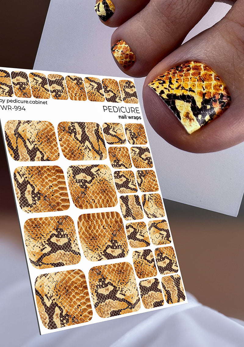 Snakeskin patterned nail wraps with a hand displaying similar design.