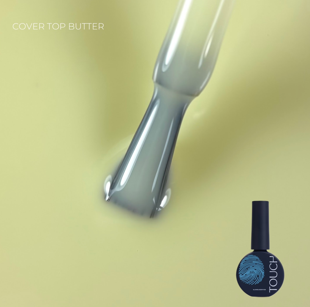 A bottle of TOUCH brand gel nail polish in the shade Cover Top Butter, shown next to a glossy brush coated with the pale yellow polish, on a solid pale yellow background.