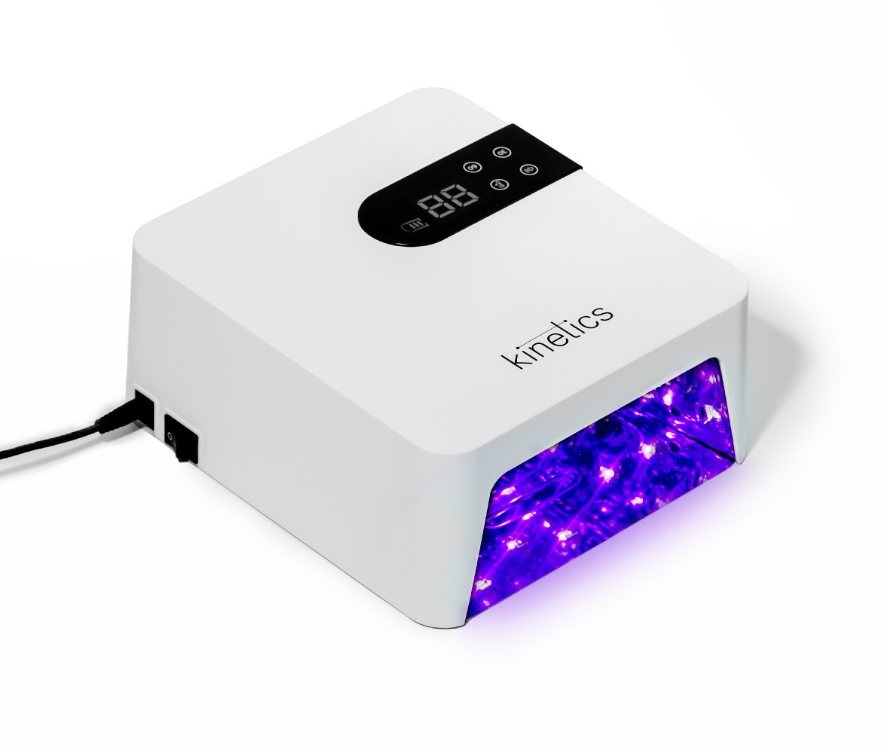 A white Kinelics UV LED nail dryer with a digital temperature display on top and a glowing purple LED light compartment, shown on a white background.