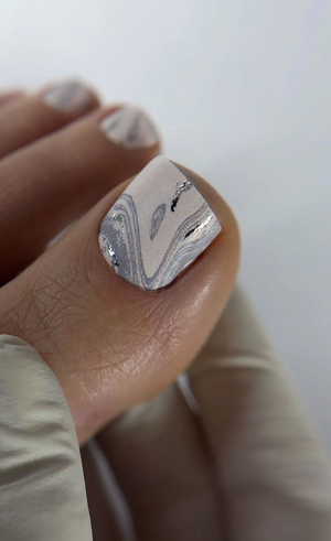 Nail with marble design held by a hand against a neutral background