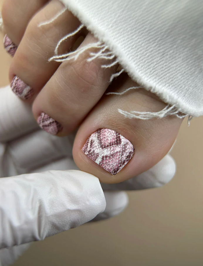 Close-up of a hand with textured pink nail polish on a neutral background