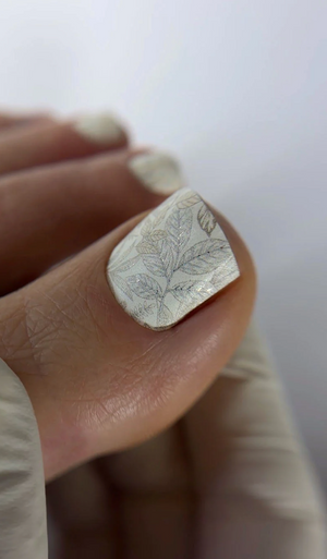 Silver ring with leaf design on a finger against a white background