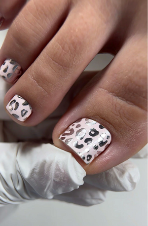 Close-up of a hand with leopard print nail design on a neutral background