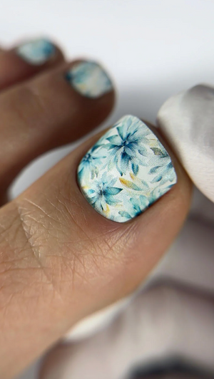 Close-up of a hand with floral nail art on a neutral background