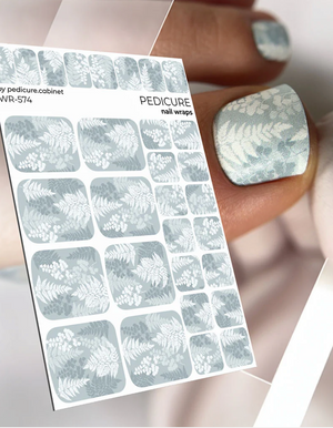Sheet of nail wraps with a floral design and a sample on a person's nail.