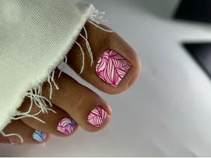 Toes with pink and white zebra pattern nail design on a light background