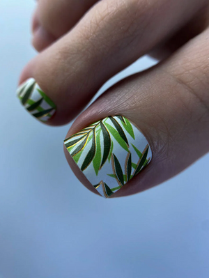 Dark nail wrap WR‑752 with bright green leaf pattern applied on toenails, close-up view of pedicure design