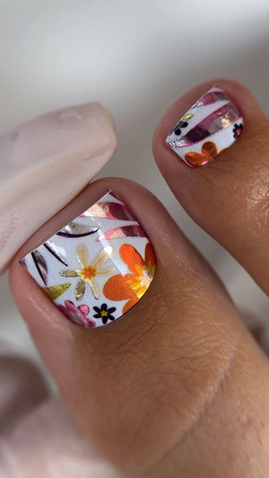 Close-up of a hand with floral nail art on a neutral background