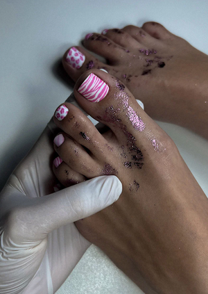 Close-up of feet with pedicure and a hand wearing a glove.