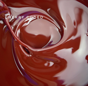 A close-up of glossy, swirling cherry-colored liquid with the text 'CHERRY CODED' overlaid in white near the upper left.