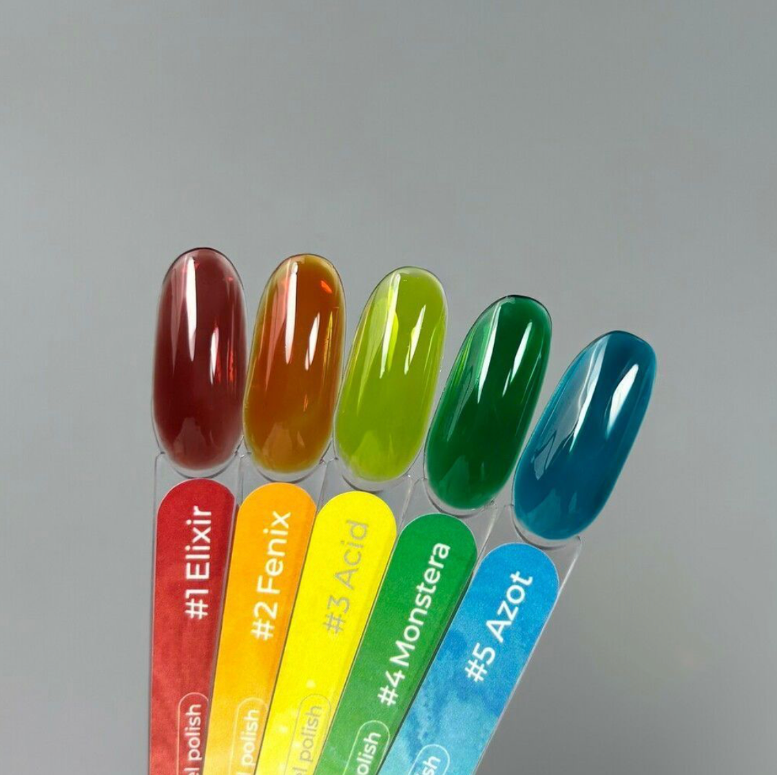 Set of five nail polish samples with colorful labels on a gray background